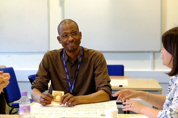 Two Teachers On A Trainingg Course Seated At A Table